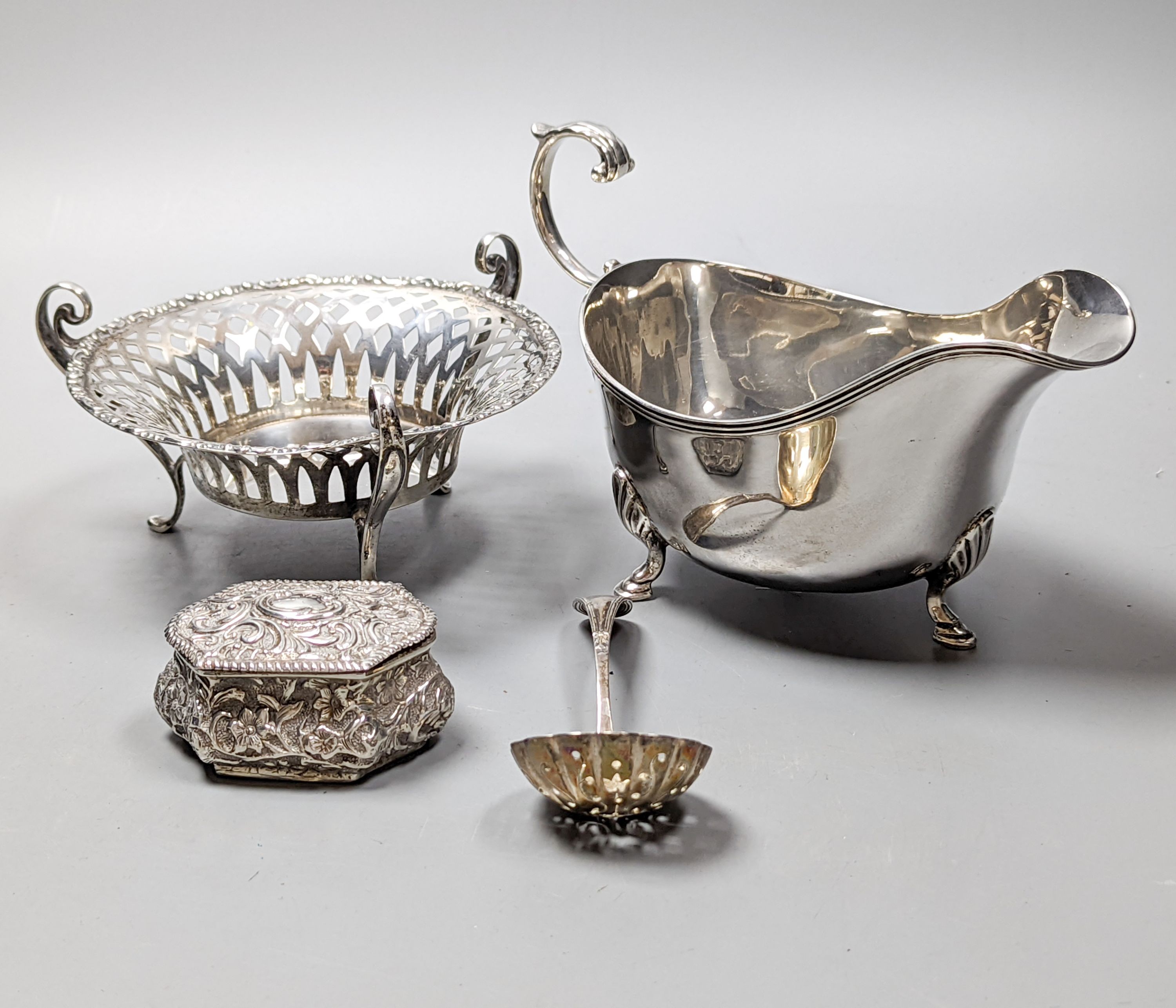 A George V silver sauceboat by Mappin & Webb, Birmingham, 1911, an Edwardian silver tri-handled bowl, a late Victorian repousse silver box and a George V silver sifter spoon, 11oz.